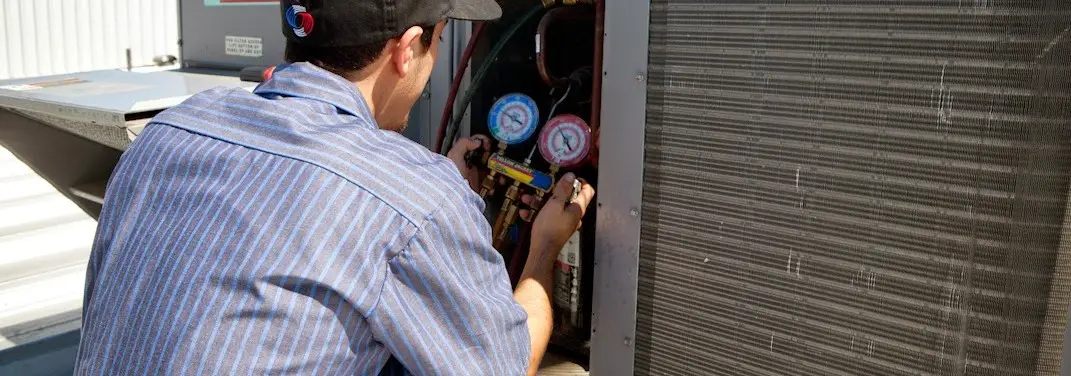 HVAC technician servicing a condenser unit in Clarkston